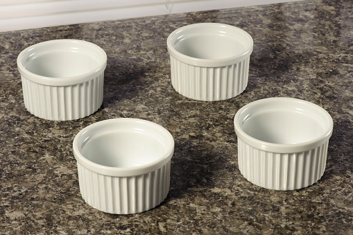 Set with four white ceramic ramekins, on a marble top