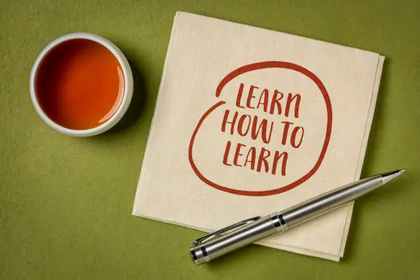 learn how to learn inspirational note note on a napkin with a cup of tea, education and personal development concept