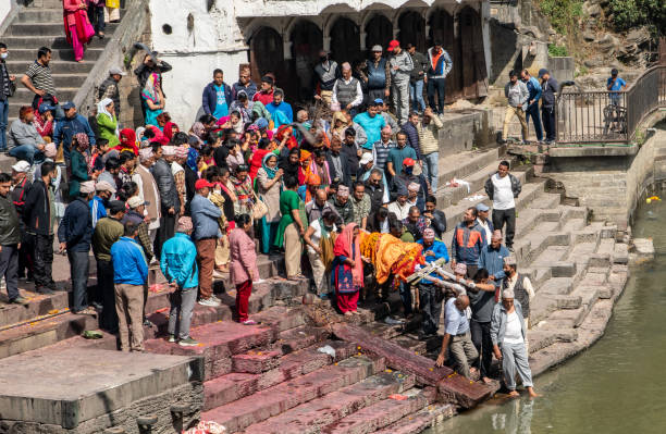 Hindu purification ceremony before cremation Kathmandu , Nepal - oct 30, 2019: relatives of the deceased carry the body on the ghats of the Bagmati River to purify it before cremation in Pashupatinath, Kathmandu kathmandu stock pictures, royalty-free photos & images