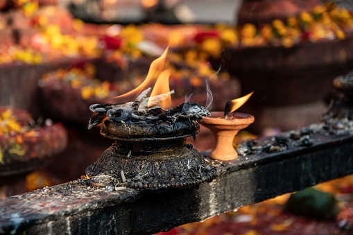 Lit oil and butter candles scatter their sacred and fragrant smoke on the morning of the Budhanilkantha temple in Kathmandu