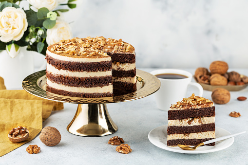 Freshly prepared delicious chocolate cake with walnuts on a white table on a cake stand