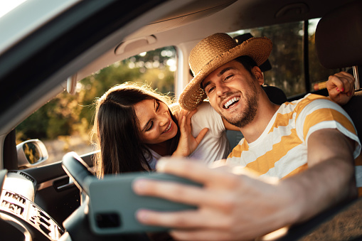 Happy young couple taking selfie in a car