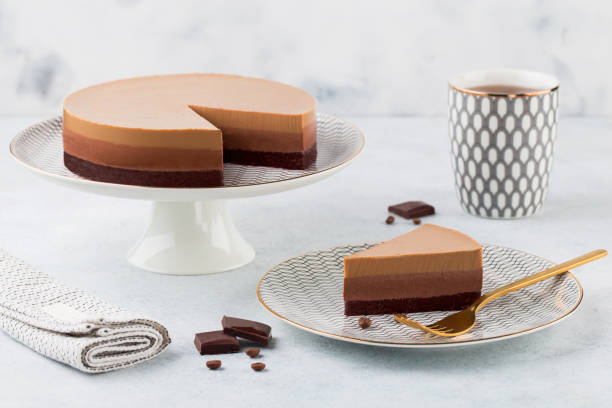 Triple chocolate mousse cake on a cake stand on white background