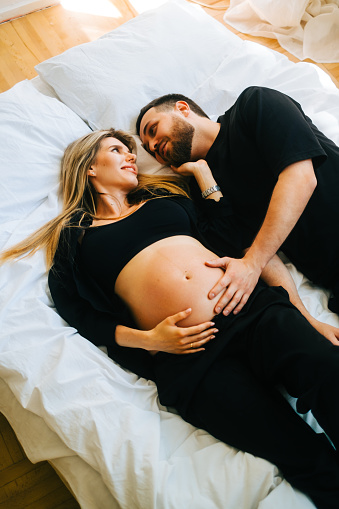 Future mother and father clasped pregnant big tummy. husband hugs pregnant wife. Happy family resting at home