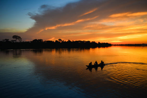 The silhouette of a small canoe on the Guaporé river at dusk stock photo