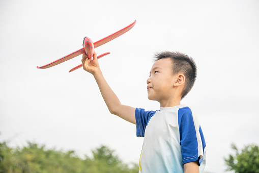 A little boy playing with a plane on the park lawn