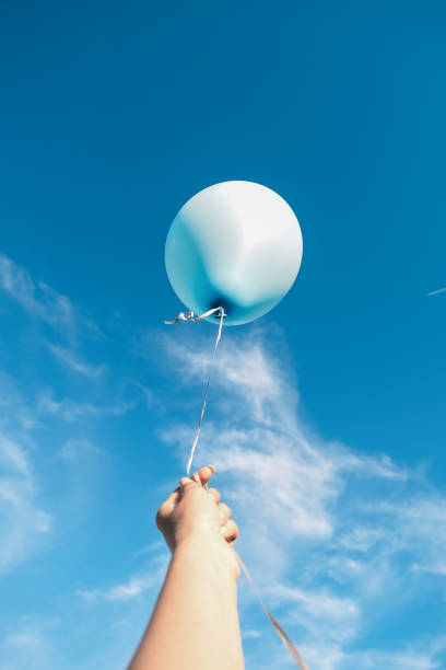 istock A woman's hand holds a balloon against the blue sky. Selective focus 1413151886