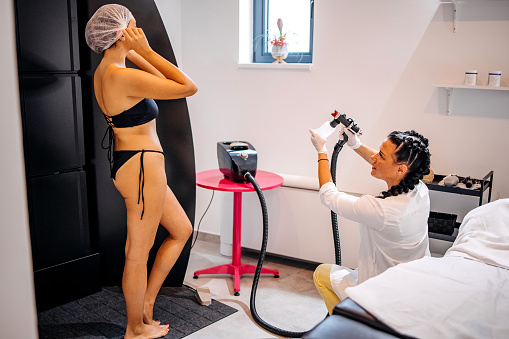 Happy young woman receiving spray tan treatment at the spa