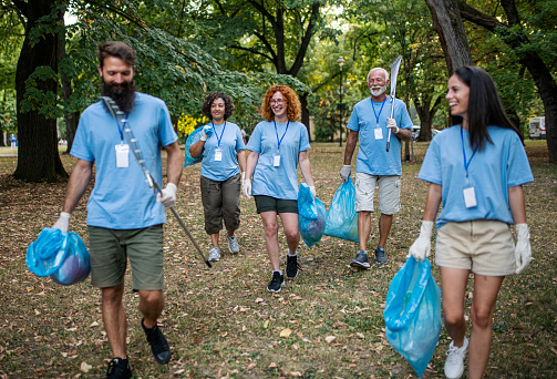Group of volunteers picking up trash and plastic in public park