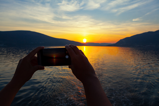 Smartphone in the hands photographs the sunset . Taking a photo of twilight