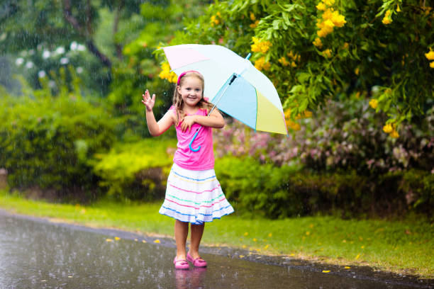 istock Kid with umbrella playing in summer rain. 1413161961