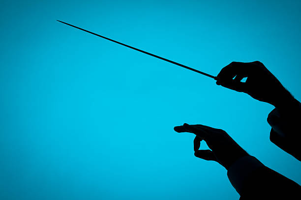 Conductor Male orchestra conductor hands, one with baton. Silhouette against blue background. musical conductor stock pictures, royalty-free photos & images
