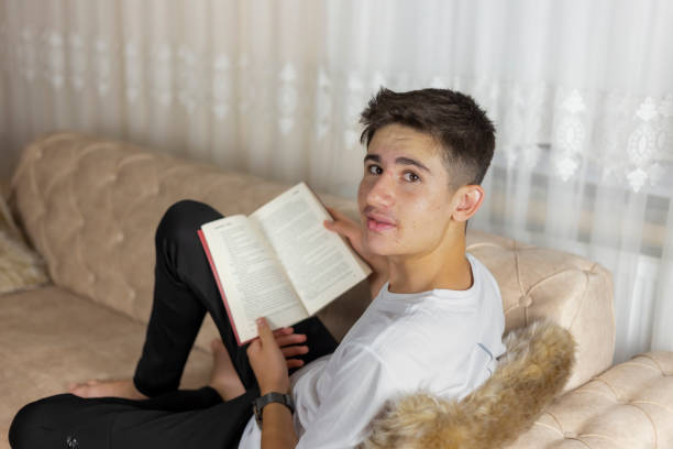 istock Young man reading a book at home. 1413164647