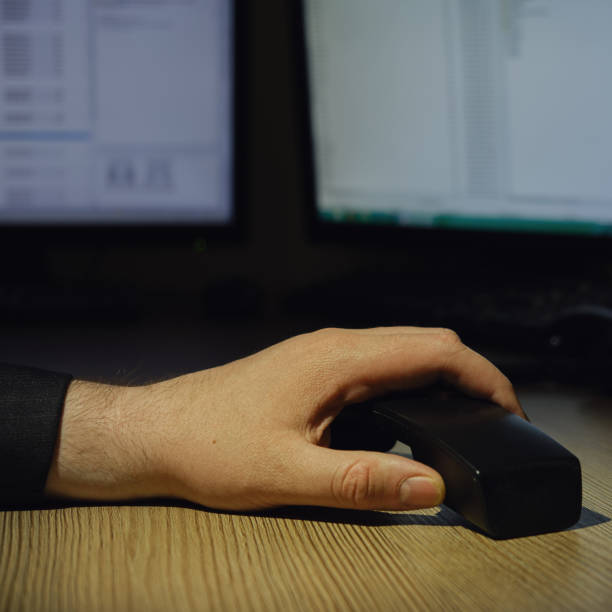 istock A hand holds a landline phone handset on an office desk with computer monitors 1413170124