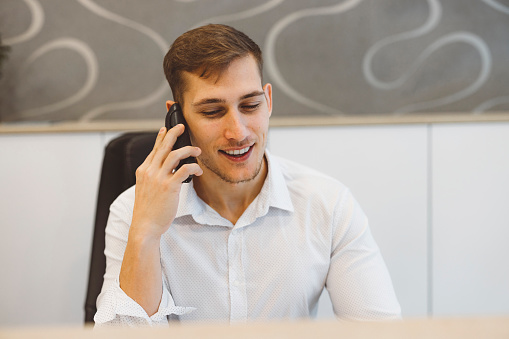 Receptionist talking on the landline phone at work, answering calls at the front desk.