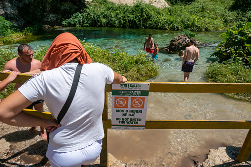 Sarande, Albania July 10, 2022 Visitors to the Blue Eye cold spring in the mountains and a sign says No Swimming