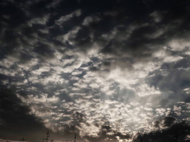 Sunset or sunrise. Clouds in the evening or morning sky. Sun rays. Beautiful landscape. Black and white monochrome photography in retro or vintage style. Increased level of photo noise as an art trick puesta de sol o salida del sol. nubes en el cielo de la tarde o de la mañana. los rayos del sol perforan las nubes. fotografía monocromática en blanco y negro en estilo retro o vintage. aumento del nivel de ruido fotográfico como truco de arte