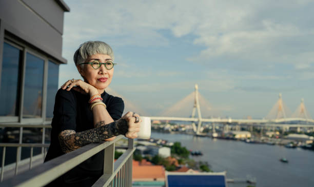 Asian Senior woman at  pleasures home Asian Senior woman drinks coffee on the balcony with a view of the river happily scene scented stock pictures, royalty-free photos & images