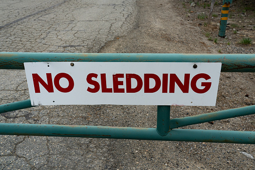 No Sledding sign on closed road in the forest