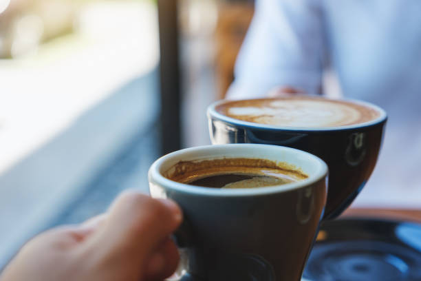 immagine in primo piano di un paio di persone che tintinnano tazze di caffè bianche nel bar - morning coffee coffee cup two objects foto e immagini stock