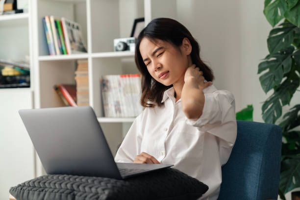 Tired young woman with neck pain because using the computer and working for a long time at home. stock photo