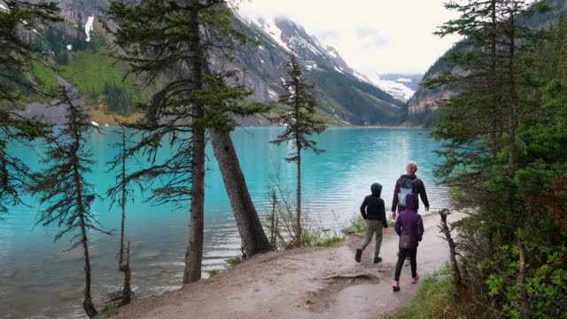 Family hiking around a pristine glacial lake in Banff National Park