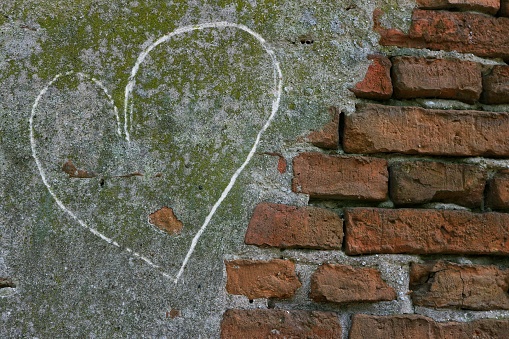 A heart drawn on plaster covering part of a brick wall.