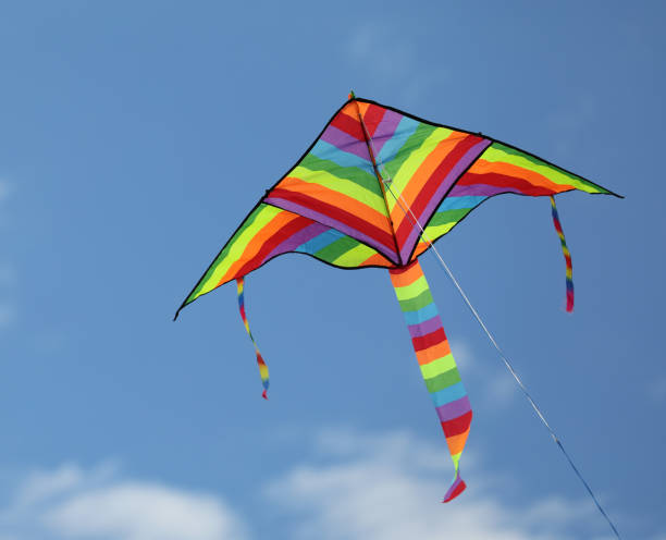 istock colorful triangular kite that flies high in the sky with some clouds tied to a thread 1413192365