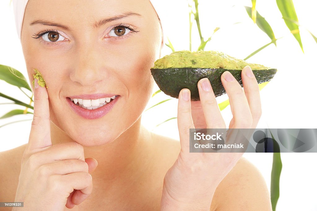 Avocado facial mask A portrait of a young woman applying natural avocado mask on her face Adult Stock Photo