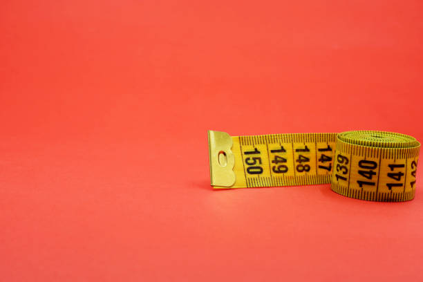 istock yellow measuring tape on a red background 1413196367
