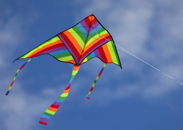 istock colorful triangular kite flying high in the blue sky with some white clouds tied to a thread 1413197074