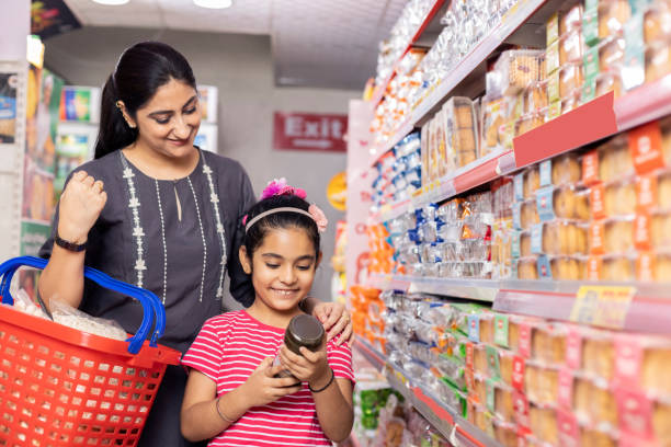 happy mother and daughter reading product information while shopping at supermarket - asian ethnicity shopping mall supermarket store imagens e fotografias de stock