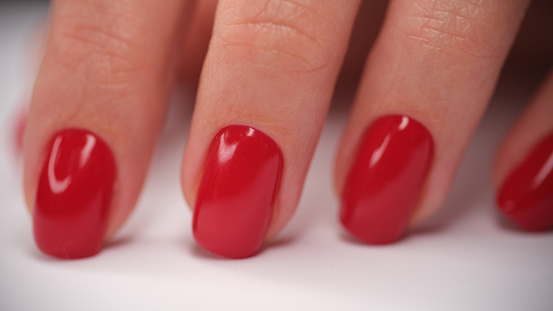 Close-up of female hand with perfect red glossy manicure. Beautiful woman fingernails with gel polish. Beauty salon and body care concept