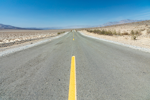 empty straight road thru the death valley with yellow median, USA