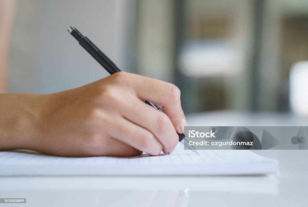 Close up of a woman's hand with pen writing on a notebook Handwriting Stock Photo