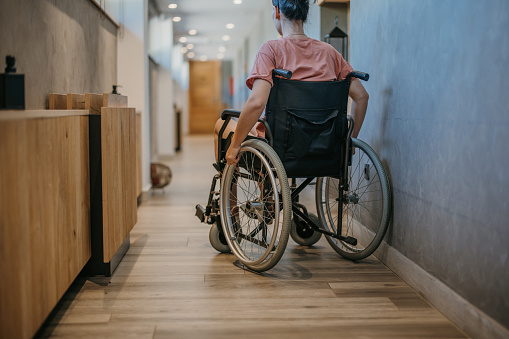 Young woman sitting in wheelchair and moving through building hallway