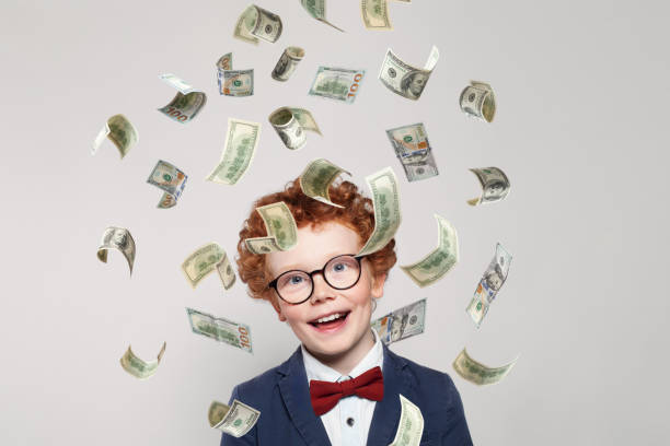 istock Curious redhead little kid boy with us dollar money rain on white background 1413205408
