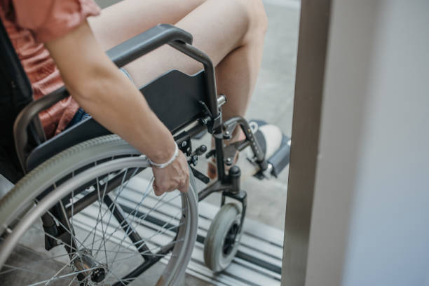 Young woman in wheelchair entering the elevator stock photo