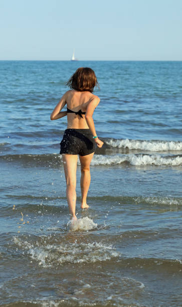 istock slender athletic young girl running barefoot on the seashore 1413205610