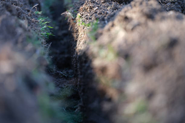 istock Trench in ground for electrical or internet cable at construction site 1413205629