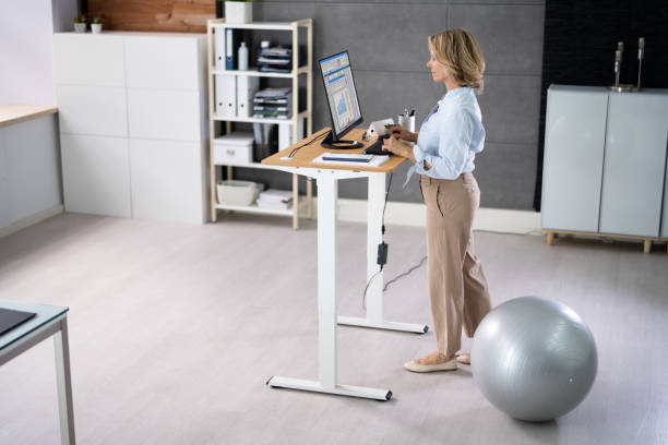 istock Woman Using Adjustable Height Standing Desk In Office 1413205663