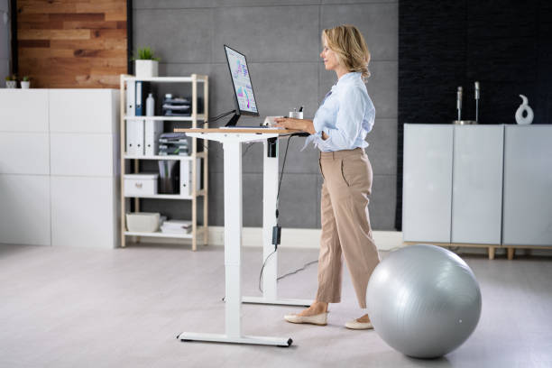 istock Woman Using Adjustable Height Standing Desk In Office 1413205679