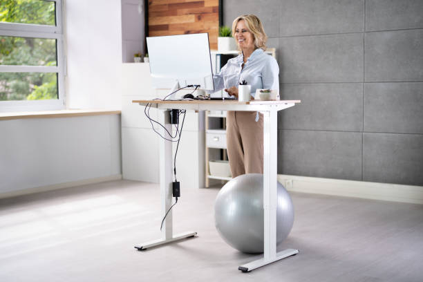 istock Woman Using Adjustable Height Standing Desk In Office 1413205694