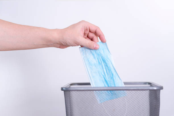 istock A man's hand throws a used medical mask into a trash can. 1413205720
