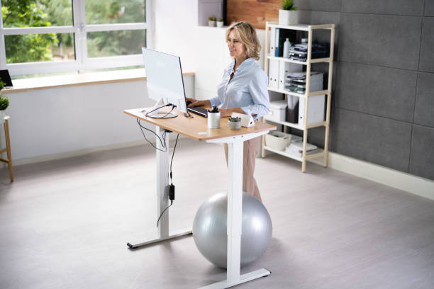 istock Woman Using Adjustable Height Standing Desk In Office 1413205726