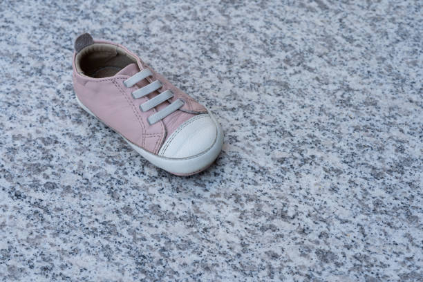 one pink baby shoe on a marble background. concept of child abuse, kidnapping or pedophilia. - paedophilia imagens e fotografias de stock