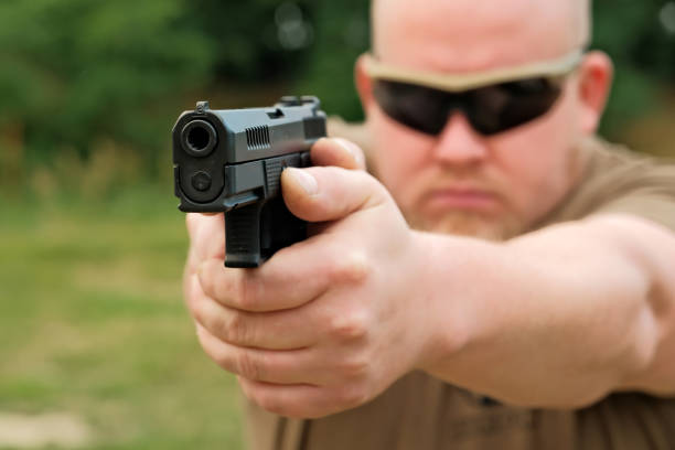 istock a man threatens with a combat pistol. man holding a gun in his hands 1413214965