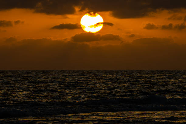 A big sun, black clouds, on the sea