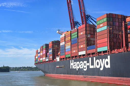 Hamburg, Germany, August 3, 2022: Hapag-Lloyd container vessel shipping international freight on the cargo port of Hamburg on the river Elbe, blue sky, copy space, selected focus