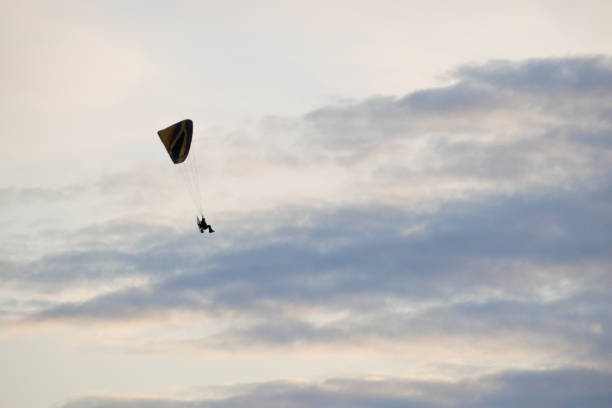 雲のある空を飛ぶパラグライダーのシルエット - extreme sports high up sport outdoors ストックフォトと画像